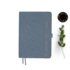 Gray fabric-covered notebook with rounded corners, matching elastic band, pen loop, and dual ribbon bookmarks, shown with a green leafy branch and a floral 'joie' logo